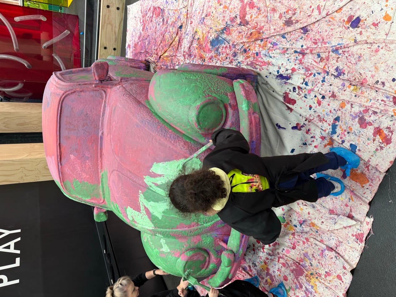 Children painting a VW Beetle sculpture during a hands-on excursion activity.