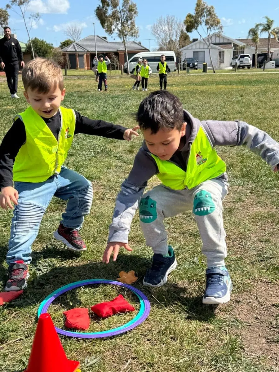 Children playing in a garden activity area with tyres and natural elements.