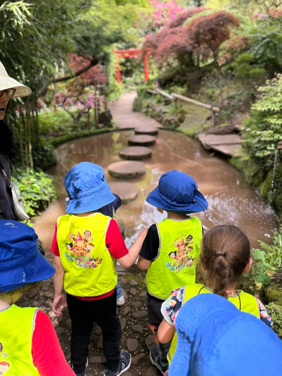 A small group of children walking together through a garden setting.