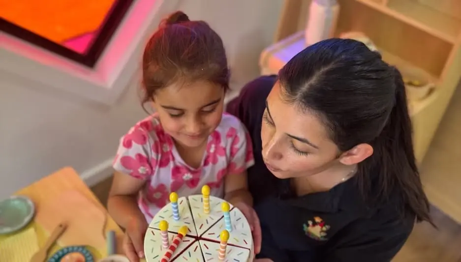 A child sharing a celebratory classroom moment with an educator at Kids Kingdom.