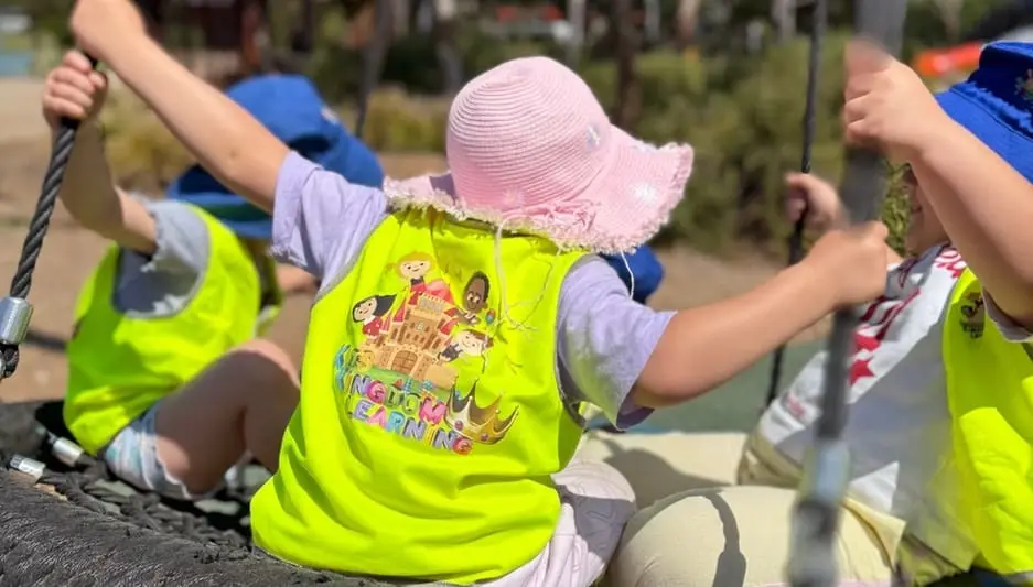 Children enjoying group swing play during outdoor time at Kids Kingdom.
