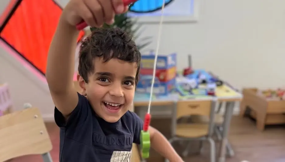 A child lifting magnetic play pieces during an indoor learning moment at Kids Kingdom.