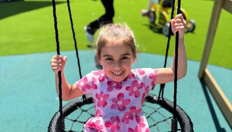A child smiling on the outdoor nest swing at the Hoppers Crossing centre.
