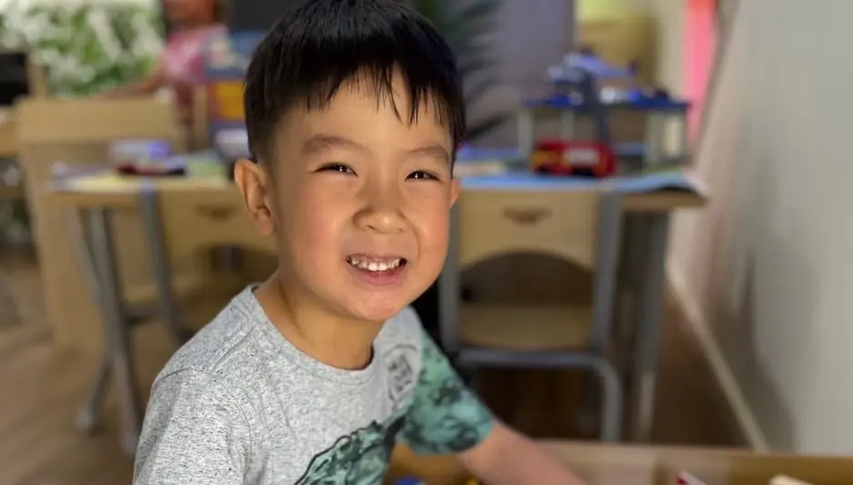 A smiling child indoors during a calm classroom moment at Kids Kingdom.