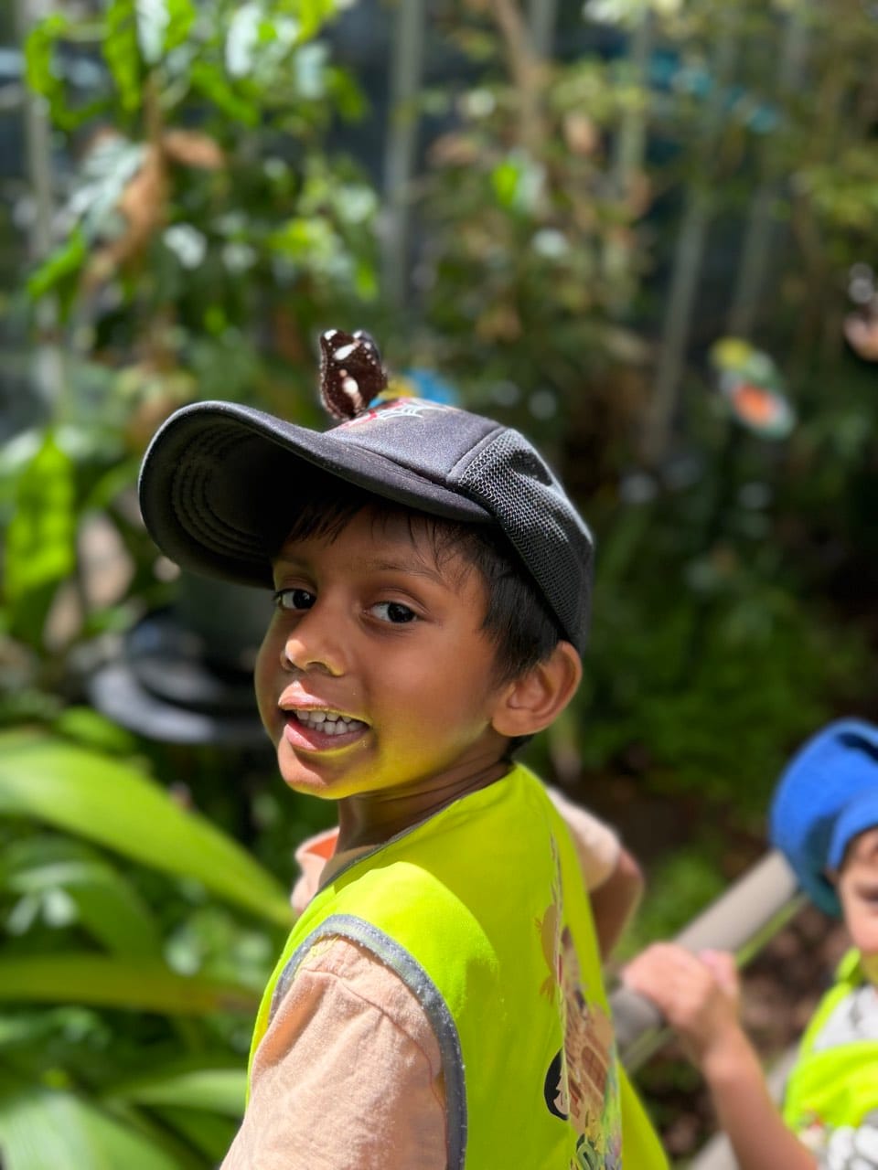 A child smiling outdoors in a hat during a supervised excursion.