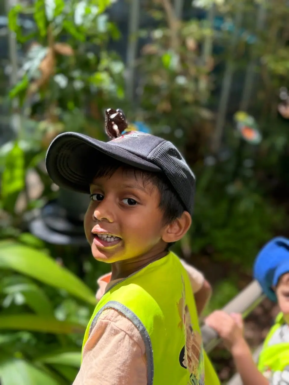 A child smiling outdoors in a hat during a supervised excursion.